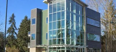 Newcastle City Hall exterior on a cloudy Pacific Northwest afternoon, a municipal building with a parking lot and evergreen trees in the foreground.