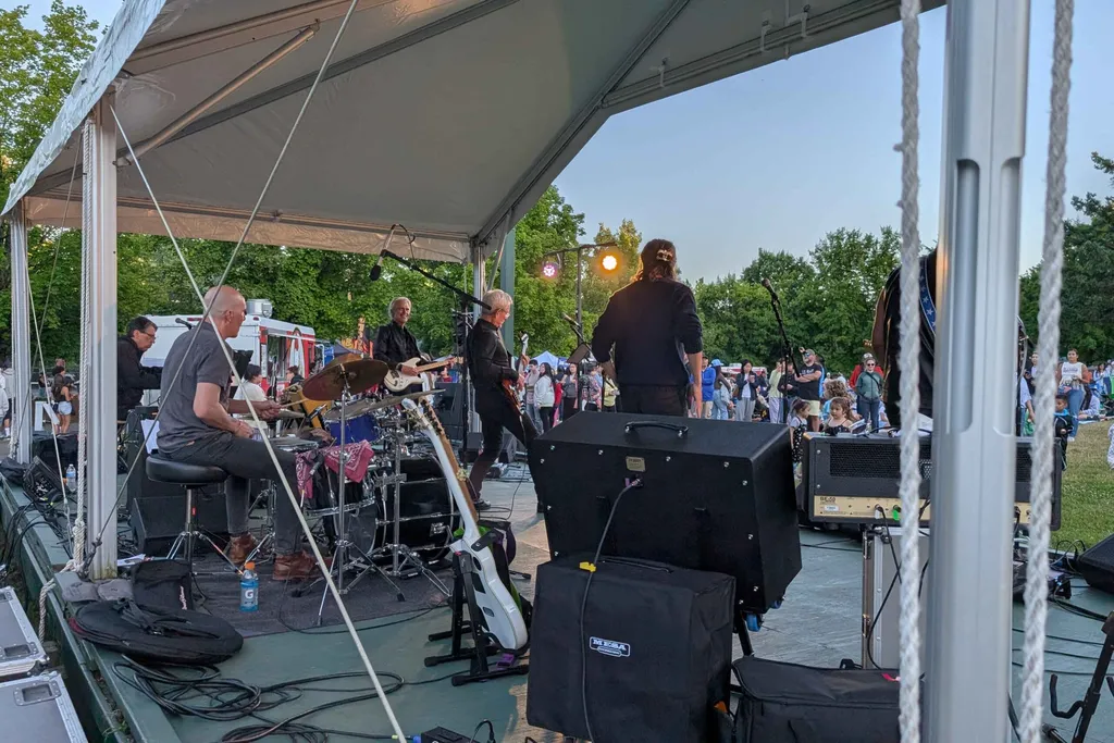 Crowd relaxing on the lawn at Lake Boren Park enjoying a live outdoor concert on a summer evening.