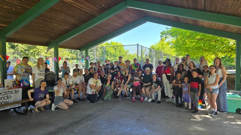 Pride attendees smiling and waving rainbow flags at Lake Boren