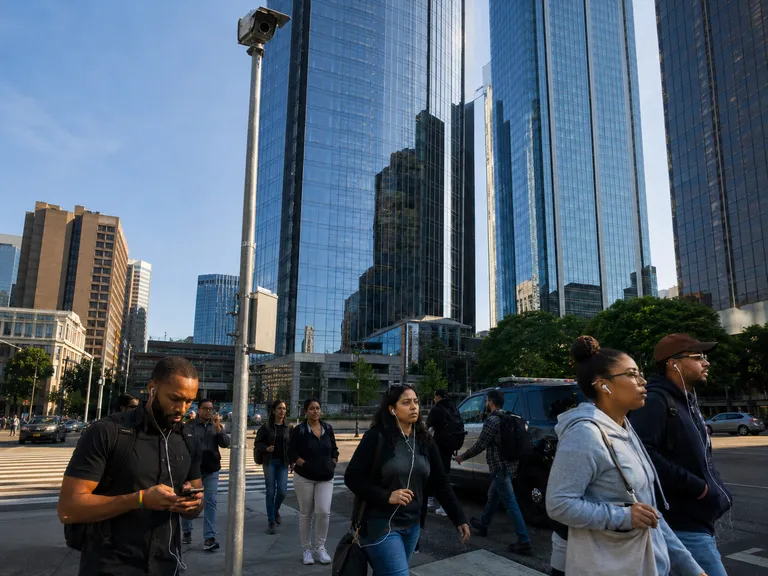 A surveillance camera mounted on an urban Seattle street corner, corporate office buildings and a police cruiser visible in the background, documentary photography style.